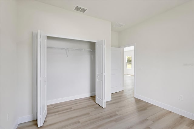 unfurnished bedroom featuring light wood-type flooring and a closet