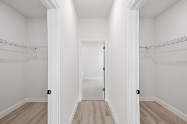 walk in closet with light hardwood / wood-style floors