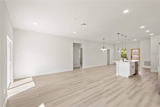 unfurnished living room with sink and light hardwood / wood-style floors