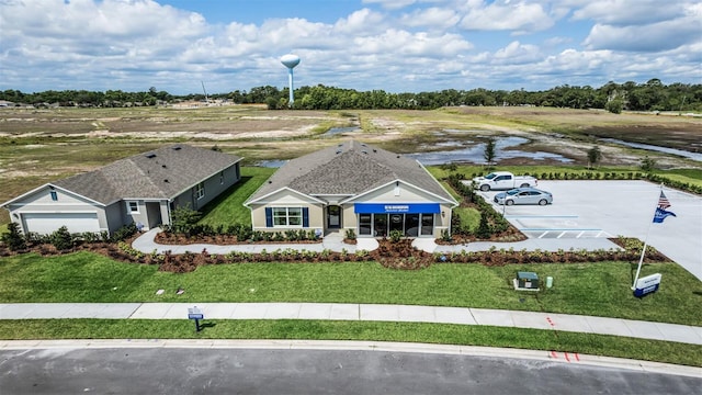 view of front of home featuring a water view, a garage, and a front lawn