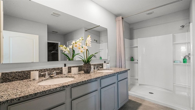 bathroom with a shower, tile patterned floors, and double vanity