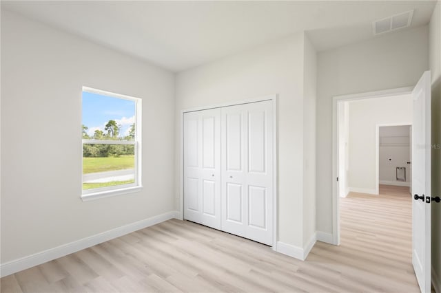 unfurnished bedroom featuring light hardwood / wood-style flooring and a closet