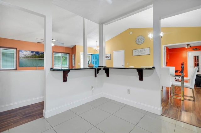 701 Castlewood Dr, Winter Springs, FL 32708 - kitchen featuring a breakfast bar area, light tile patterned flooring, ceiling fan with notable chandelier, vaulted ceiling, and kitchen peninsula