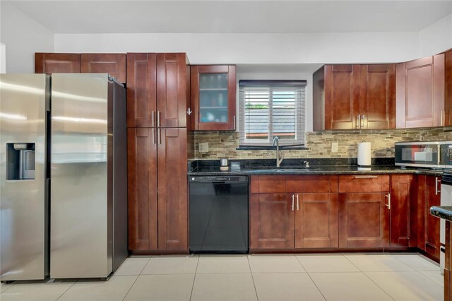 kitchen featuring dark stone countertops, light tile patterned floors, appliances with stainless steel finishes, decorative backsplash, and sink