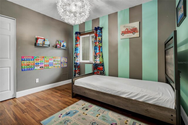 bedroom with an inviting chandelier, a textured ceiling, and hardwood / wood-style flooring