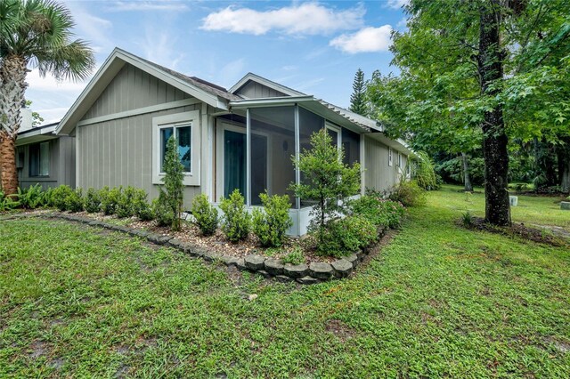 view of home's exterior featuring a sunroom and a yard