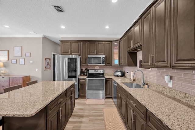 kitchen with dark brown cabinetry, sink, a kitchen breakfast bar, light hardwood / wood-style flooring, and appliances with stainless steel finishes