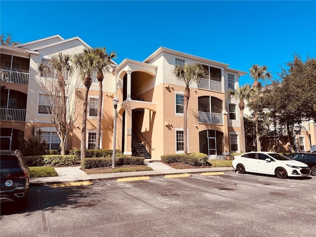 view of property featuring stairs and uncovered parking