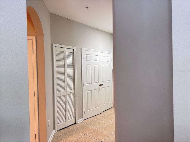 corridor with light tile patterned flooring and arched walkways