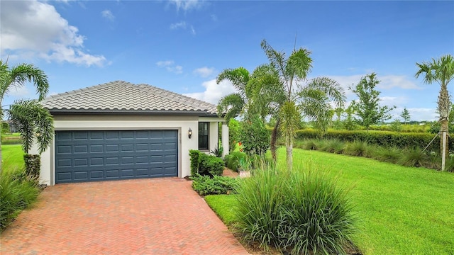 view of front facade with decorative driveway, a tile roof, stucco siding, a front yard, and a garage