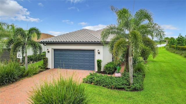 view of front facade with stucco siding, a tile roof, an attached garage, decorative driveway, and a front yard