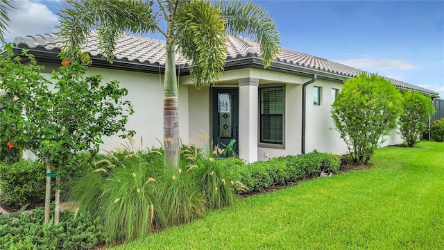 view of home's exterior featuring a tile roof, a yard, and stucco siding