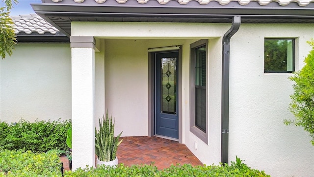 doorway to property with a tile roof and stucco siding