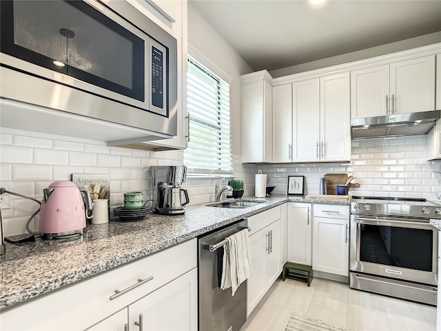 kitchen with appliances with stainless steel finishes, decorative backsplash, white cabinetry, and under cabinet range hood