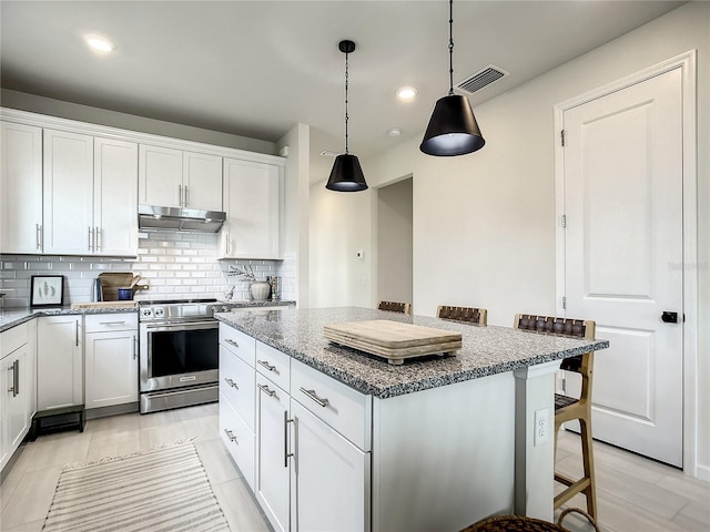 kitchen with a breakfast bar, white cabinets, under cabinet range hood, and stainless steel electric stove