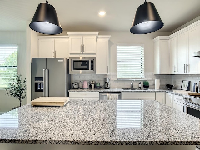 kitchen featuring white cabinetry, a kitchen island, appliances with stainless steel finishes, and a sink