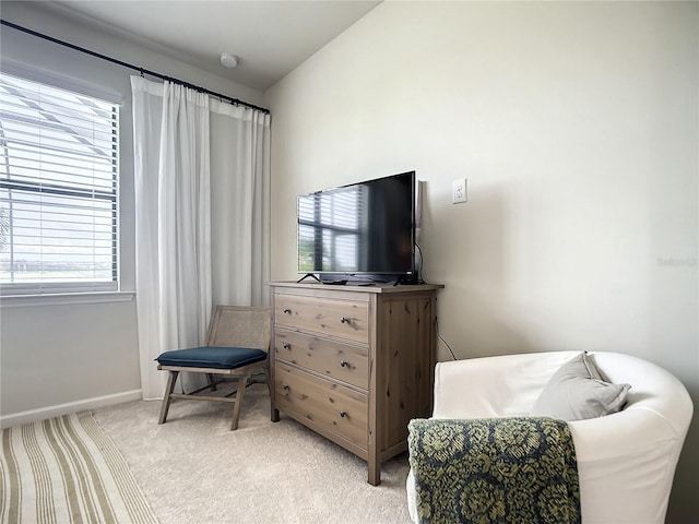 living area with lofted ceiling, light carpet, and baseboards