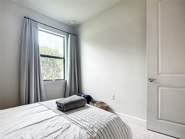 bedroom featuring light carpet and baseboards