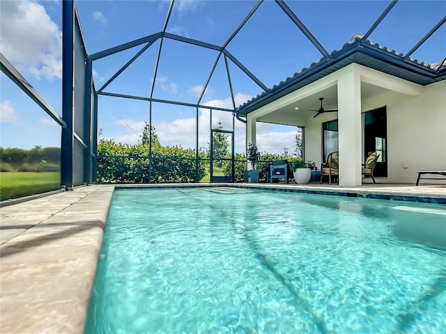 outdoor pool with a ceiling fan, glass enclosure, and a patio