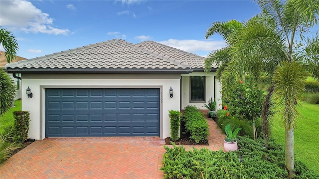 view of front of house featuring a garage, stucco siding, decorative driveway, and a tiled roof