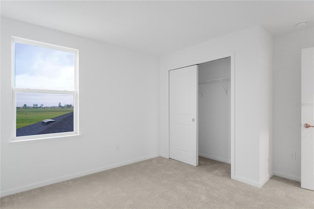 unfurnished bedroom with light carpet and a closet