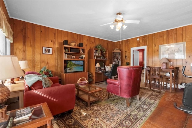 living area featuring ceiling fan, wooden walls, and wood finished floors