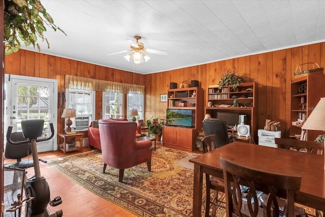 living room with wood walls, ceiling fan, and a wealth of natural light