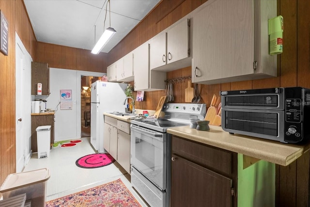 kitchen with a toaster, white appliances, wood walls, a sink, and light countertops