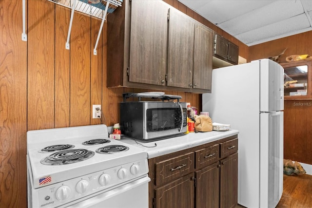 kitchen with white appliances, light countertops, and wood walls