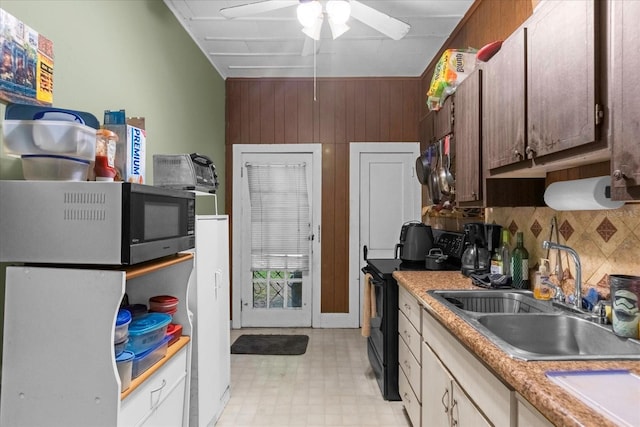 kitchen featuring light floors, light countertops, stainless steel microwave, a sink, and black / electric stove