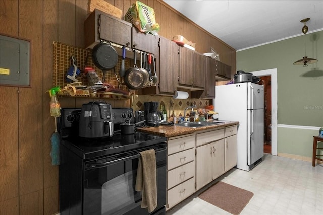 kitchen featuring black range with electric stovetop, freestanding refrigerator, crown molding, light floors, and a sink