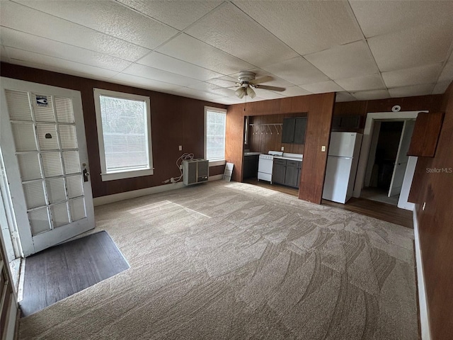 unfurnished living room featuring a paneled ceiling, light carpet, and ceiling fan