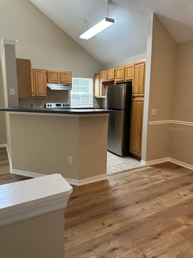 kitchen with kitchen peninsula, stainless steel fridge, light wood-type flooring, and high vaulted ceiling