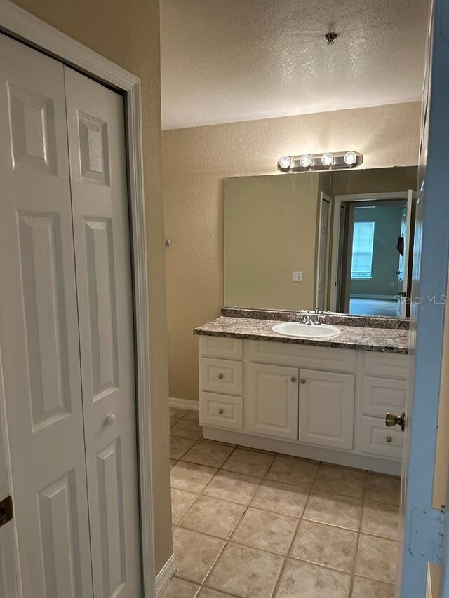 bathroom with tile patterned flooring, a textured ceiling, and vanity