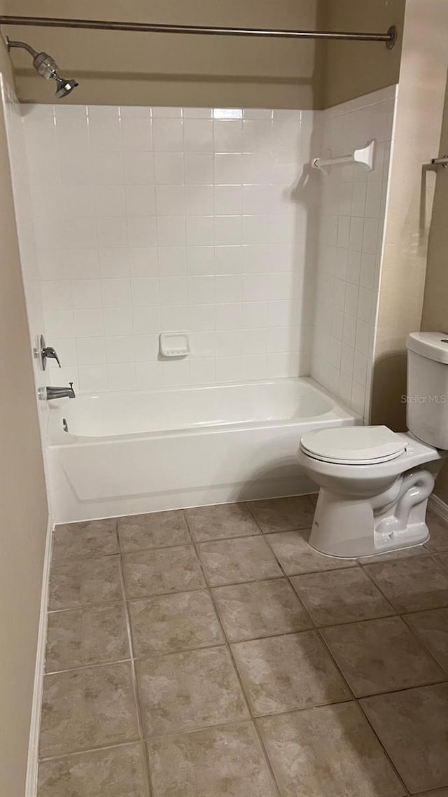 bathroom featuring tile patterned flooring, toilet, and tiled shower / bath