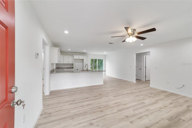 unfurnished living room featuring light hardwood / wood-style flooring, sink, and ceiling fan