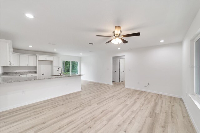 unfurnished living room with sink, ceiling fan, and light wood-type flooring