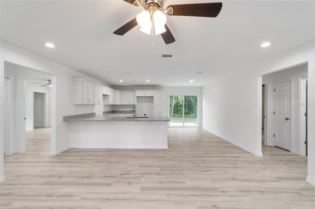 kitchen featuring white cabinets, ceiling fan, light wood-type flooring, and light stone countertops