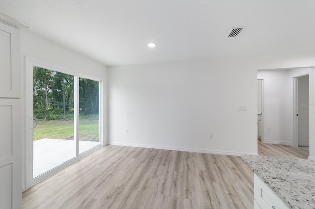 empty room with light hardwood / wood-style floors and a healthy amount of sunlight