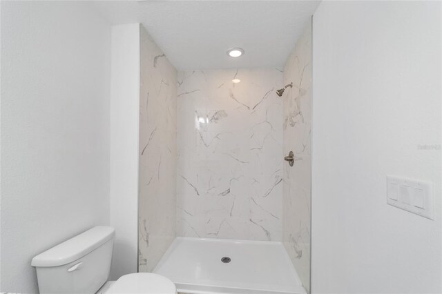 bathroom with tiled shower and toilet