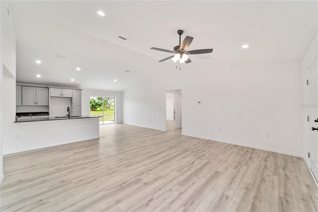 unfurnished living room with high vaulted ceiling, ceiling fan, and light wood-type flooring