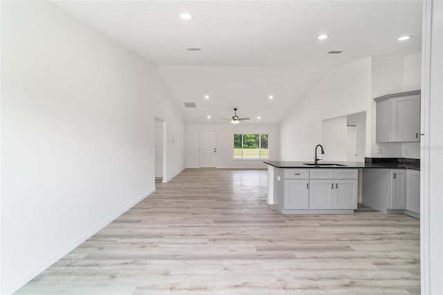 kitchen with gray cabinets, ceiling fan, high vaulted ceiling, sink, and light hardwood / wood-style flooring