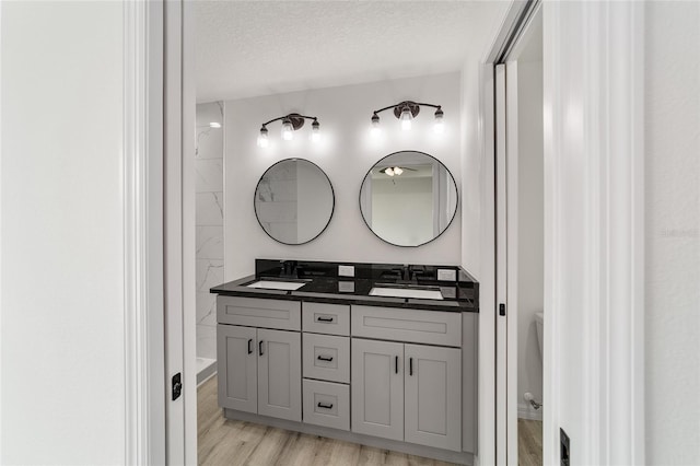 bathroom with hardwood / wood-style floors, a textured ceiling, and dual bowl vanity