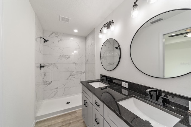 bathroom with a tile shower, hardwood / wood-style flooring, and double vanity