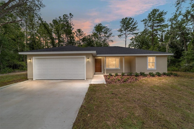 single story home featuring a garage and a lawn