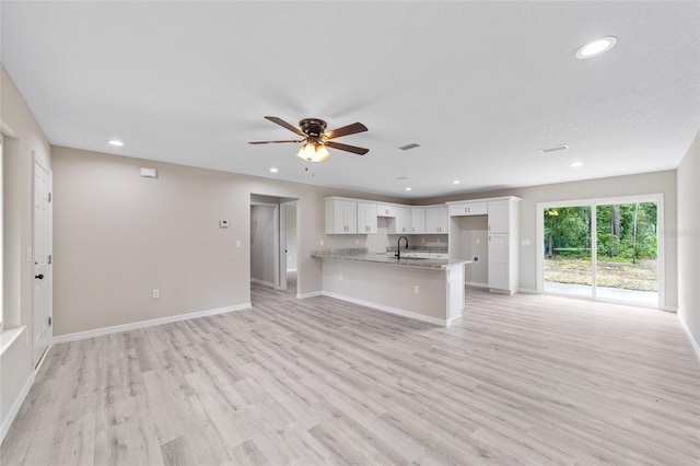 unfurnished living room with ceiling fan, sink, and light hardwood / wood-style flooring