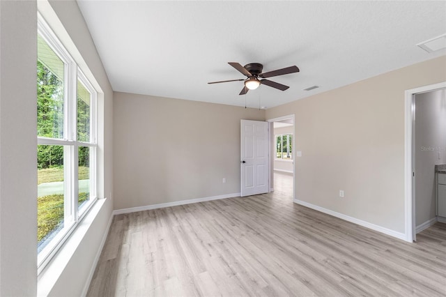 empty room featuring light hardwood / wood-style flooring, a wealth of natural light, and ceiling fan