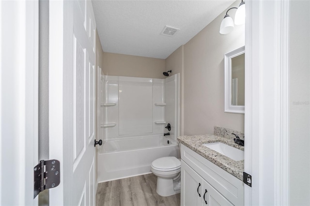 full bathroom with vanity, hardwood / wood-style flooring, shower / washtub combination, toilet, and a textured ceiling