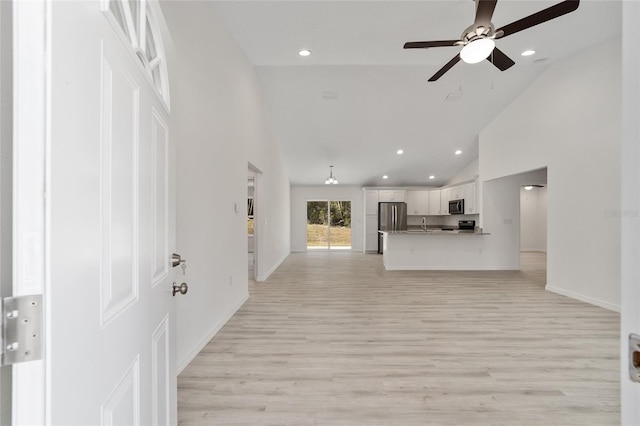 unfurnished living room with high vaulted ceiling, sink, light wood-type flooring, and ceiling fan