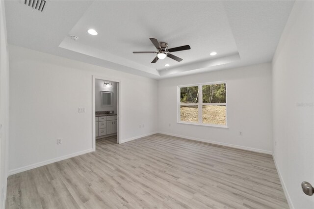 interior space featuring light hardwood / wood-style floors, ceiling fan, and a tray ceiling